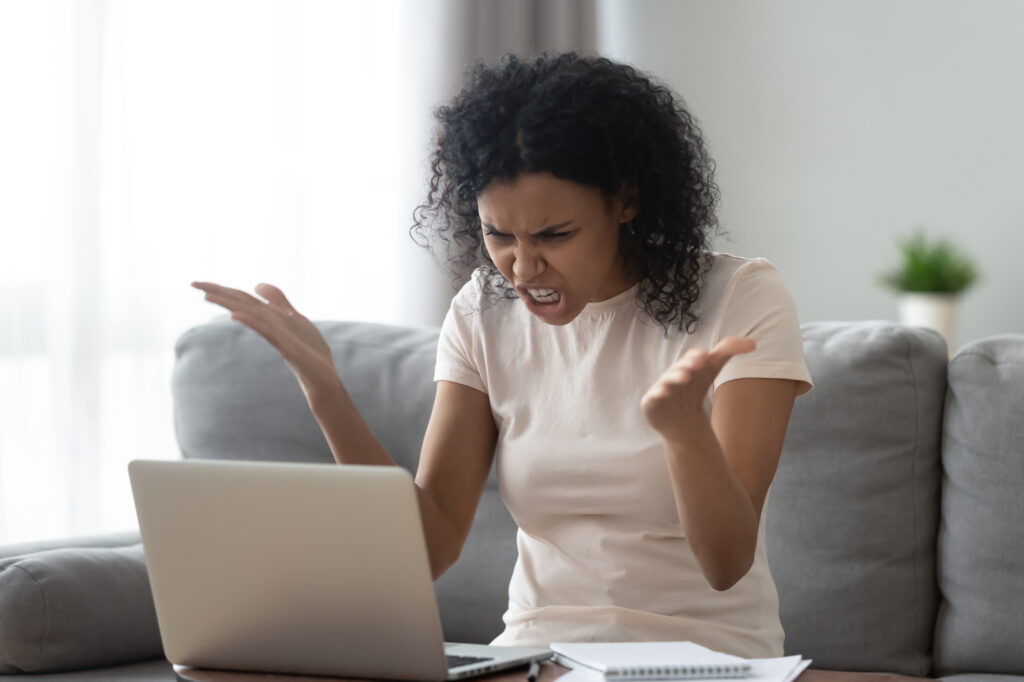 Angry stressed young black woman looking at laptop feeling annoyed Frustrated woman from slow wifi